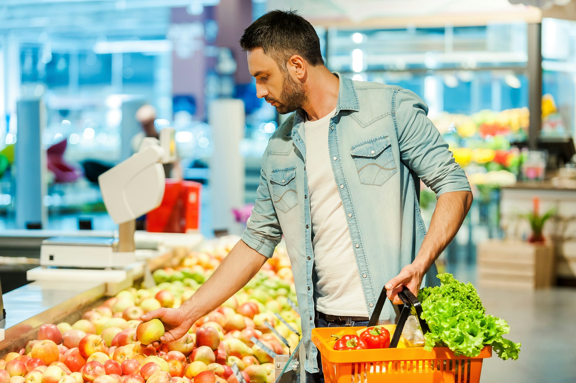 Man shopping for healthy foods in the produce section, choosing nutritious options for good oral health.
