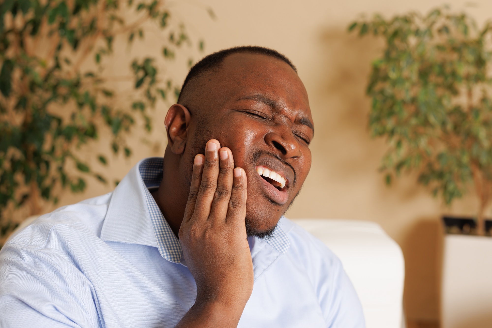 Man holding his jaw in pain, symbolizing dental emergencies like toothaches or injuries treated at Dental Associates locations in Des Moines, West Des Moines, and Grimes, IA.